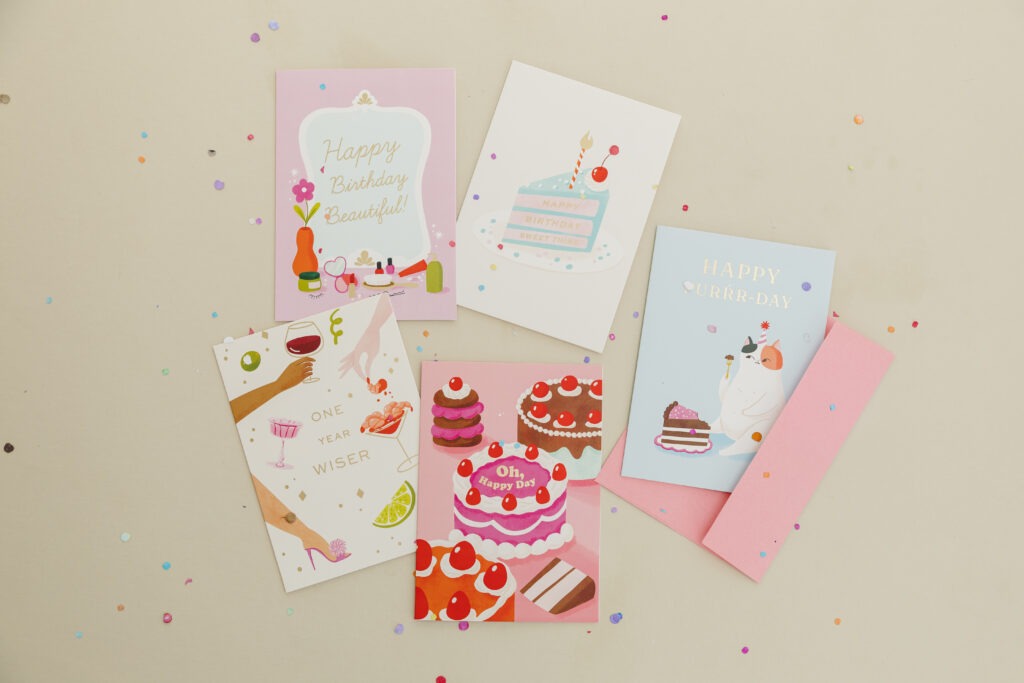 A collection of colorful birthday cards surrounded by vibrant confetti, creating a festive atmosphere.