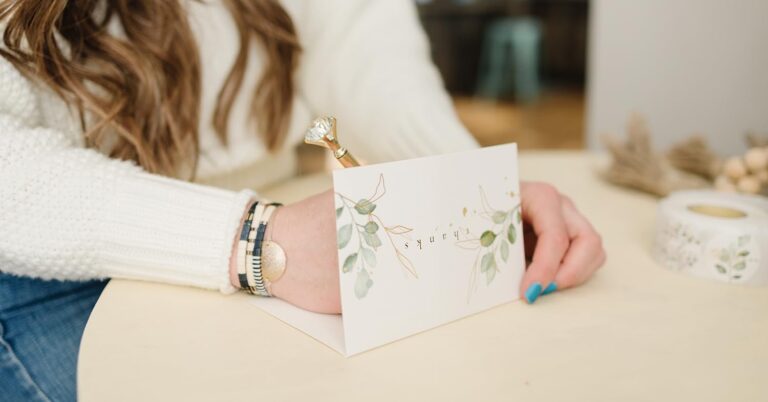 A woman holds a beautifully designed card featuring an intricate floral pattern.