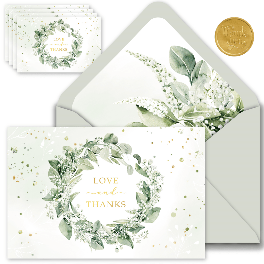 A green floral wreath surrounds elegant wedding thank you cards, conveying gratitude and love in a charming design.
