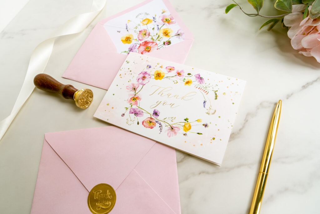 A beautifully designed pink envelope featuring floral patterns and shimmering gold foil, perfect for special occasions.